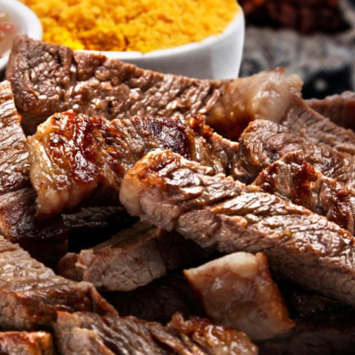 Tiras de picanha grelhadas e aceboladas com molho de churrasco e cesto de pães fatiados