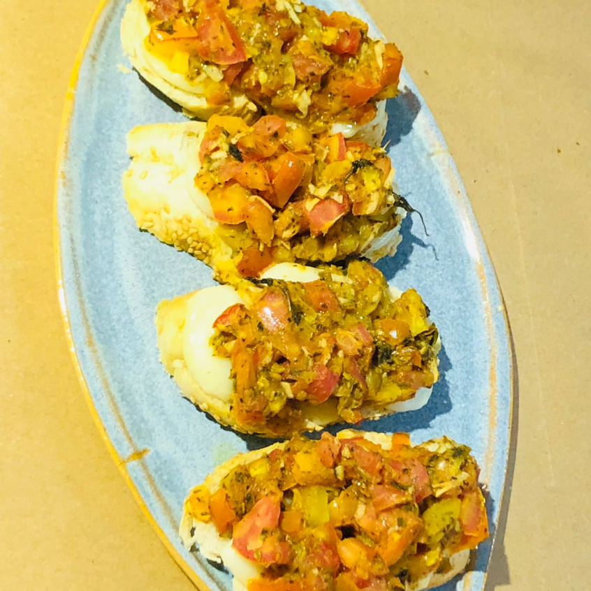 Fatias pão baguete cobertas com tomate temperado, manjericão e mussarela de búfala.