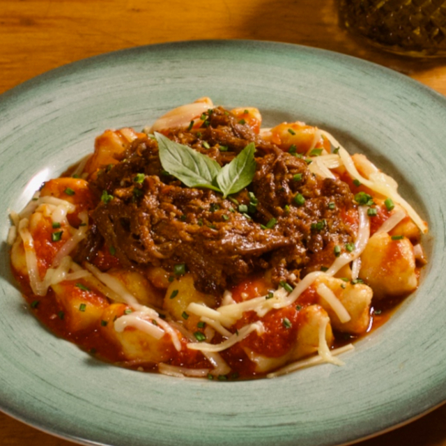 Este prato é uma celebração da excelência da culinária italiana. Nosso Nhoque de Batata Asterix é a definição da perfeição, preparado com habilidade e amor. Cada pedaço derrete na boca, revelando a suavidade da batata.  O coração deste prato é o Ragu de Costela Premium, uma carne desfiada e cozida lentamente, infundindo cada pedaço de nhoque com camadas de sabor que são simplesmente inigualáveis.  A magia acontece quando o Parmesão é maçaricado, resultando em uma crosta dourada e um sabor intenso que irradia em cada garfada.  Esta criação é um tributo à arte da culinária, onde cada elemento se une para uma experiência única e inesquecível.  Peça agora e mergulhe em um festival de sabores que é simplesmente irresistível.