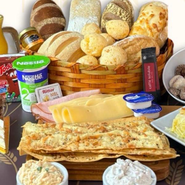 O equilíbrio perfeito entre o café e o leite! Incluso: 1 Suco de Laranja 300 ml; 1 Café Solúvel; 1 Toddynho 4 Brioches; 2 Pães Artesanais; 5 Pães de Queijo; 100 g Queijo Prato; 100 g Presunto; 2 Blister de Manteiga; 1 Bolo de Aipim Ou Bolo de Cenoura; 100 g Petit Four Doce;