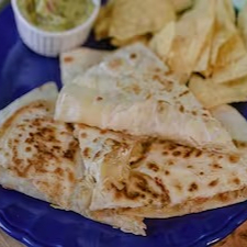 A 'Quesadilla de Abobrinha com Cenoura - Califórnia Love' é uma homenagem vibrante ao icônico rapper e ator Tupac Shakur, e sua célebre música em parceria com Dr. Dre. É uma explosão de sabores. Apresenta uma tortilla de trigo tostada à perfeição, cortada em quatro fatias generosas. O recheio é um mix de queijo derretido, abobrinha e cenoura suavemente cozida. Para finalizar, um toque de tomate fresco acrescenta uma nota de acidez deliciosa. É uma combinação harmoniosa de ingredientes que captura a essência vibrante da Califórnia e a energia inesquecível de Tupac.