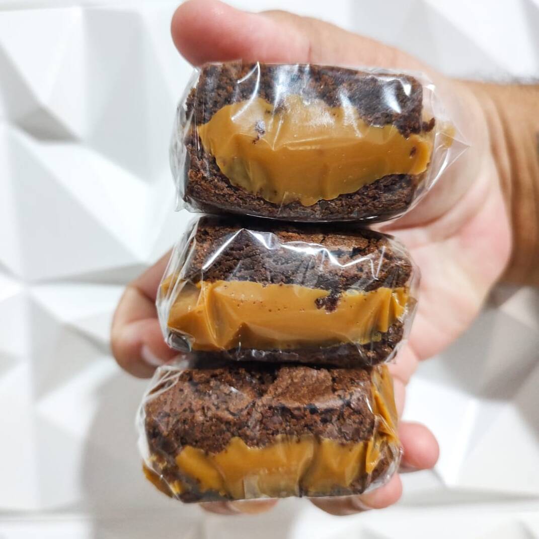 3 - Brownies Recheados Com Doce De Leite 80 Gramas e 5x5 centimetros cada.
Aquele brownie que desmancha na boca! Nossa receita exclusiva entrega uma massa densa, úmida e com o sabor intenso do chocolate nobre, recheada generosamente com doce de leite cremoso. É o equilíbrio perfeito entre o cacau e a doçura na medida certa. Cada unidade é embalada individualmente para garantir que o seu momento de prazer chegue intacto até você. Impossível comer só um!