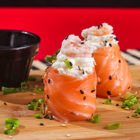 Lamina de salmão envolvendo o arroz com cream chesse e camarão na superfície.