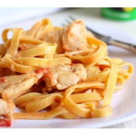 Talharim servido com cremoso molho de strogonoff de frango, feito com pedaços macios e tempero suave, resultando em um prato saboroso e reconfortante.