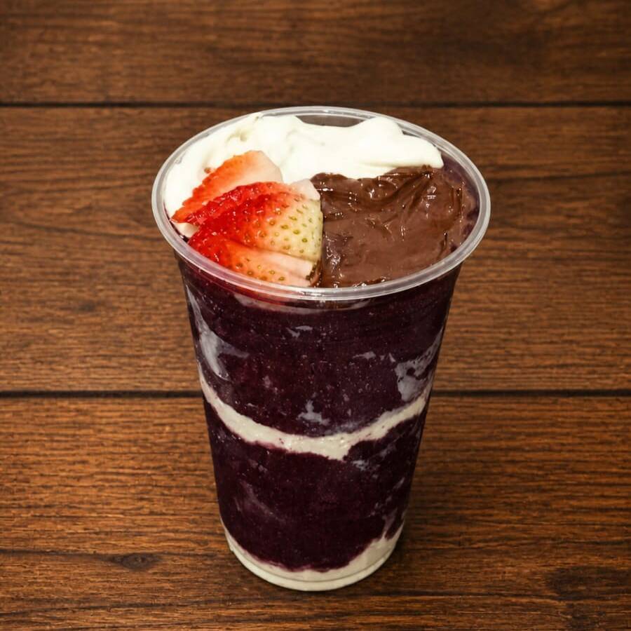 Açaí super cremoso montado em camadas de leite em pó e no topo creme de avelã leite condensado e morango