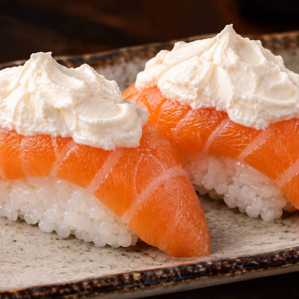 Duas unidades de nigiri de salmão fresco, regado com nosso delicioso creme chess saboroso.