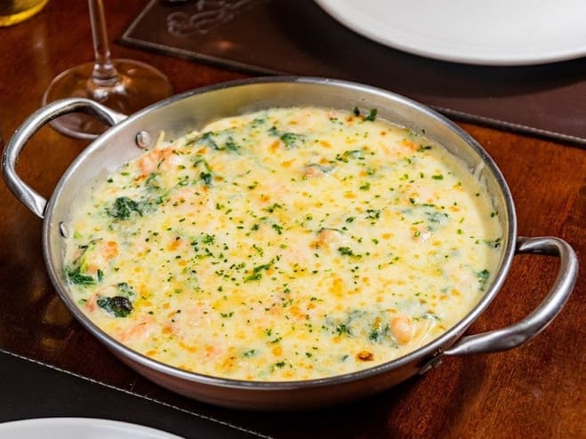 Camarões refogados com alho e cebola, flambados no vinho branco. Servido sobre espaguete ao molho bechamel e espinafre. Gratinado com queijo muçarela e parmesão.