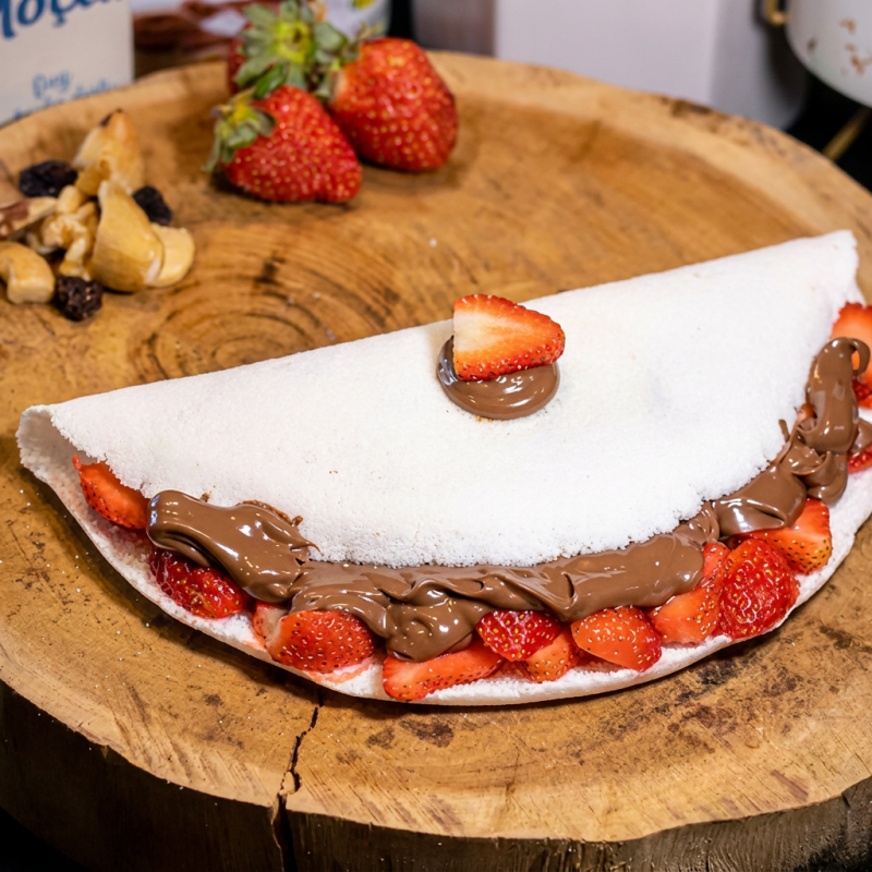 "SENSACIONAL: O nome já diz tudo!" Imagina a combinação de morangos fresquinhos com aquela Nutella cremosa escorrendo... Agora para de imaginar e vem provar! Essa é a tapioca que faz qualquer dia comum virar um evento histórico. Crocante por fora, explosiva por dentro, é o tipo de delícia que não dá pra dividir. Duvida? Experimenta e tenta não falar "UAU!" na primeira mordida. (Spoiler: impossível). Tá esperando o quê? Bora fazer história no seu paladar!