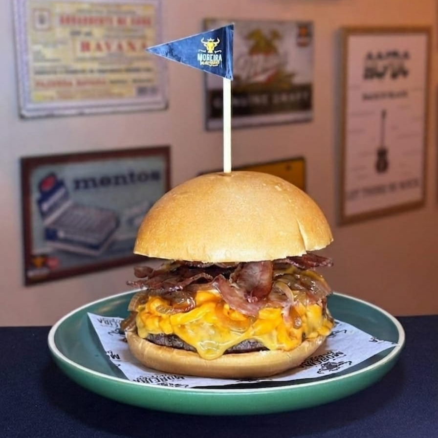 Suculento Burger Angus, Fatias de Queijo Cheddar Americano, Cebola Caramelizada, Cheddar Cremoso, Molho Barbecue Artesanal, Fatias de Bacon Crocante. Servido no Pão Levemente Selado