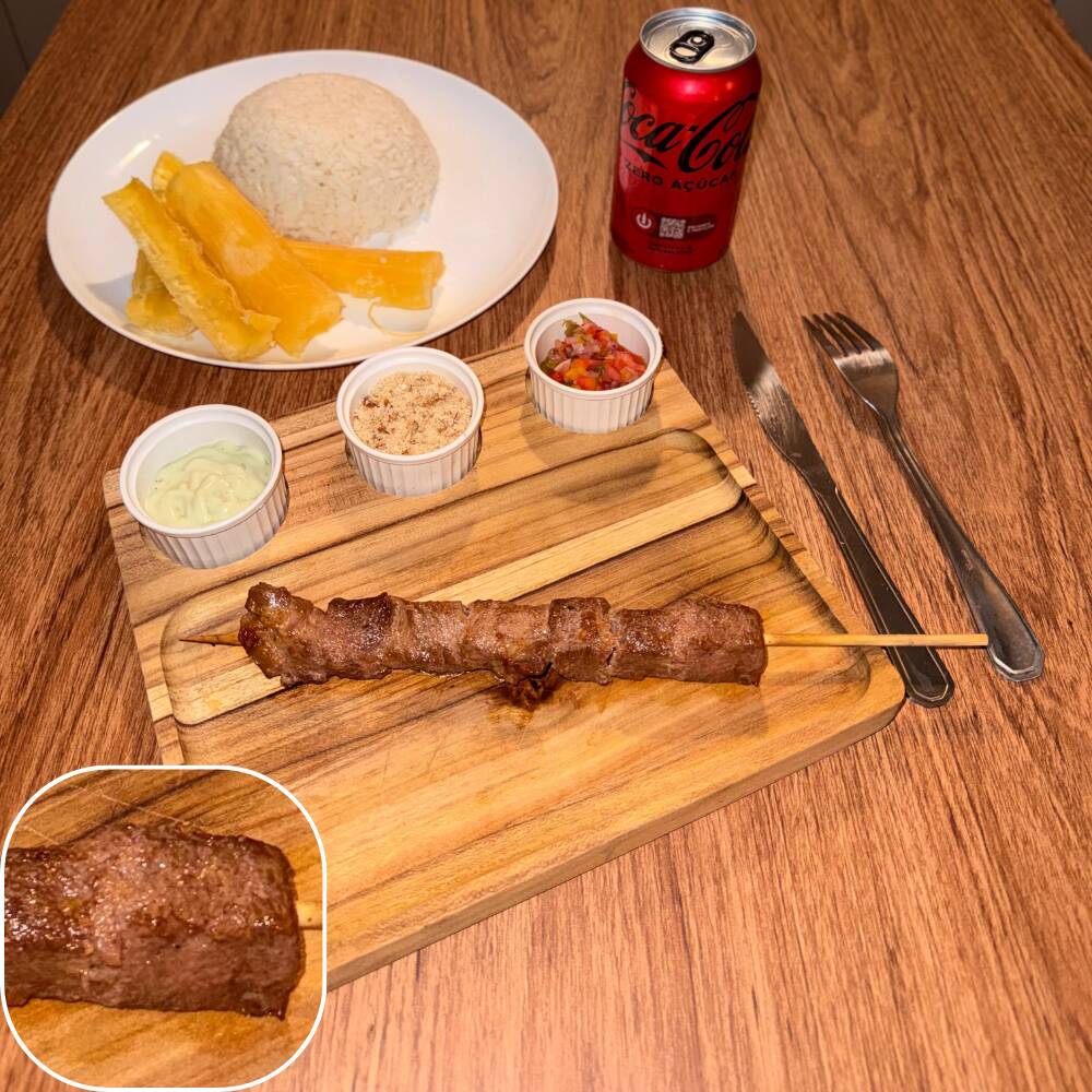 Espeto de miolo da alcatra bovina acompanhado por arroz, mandioca, vinagrete, farofa crocante e molho verde.