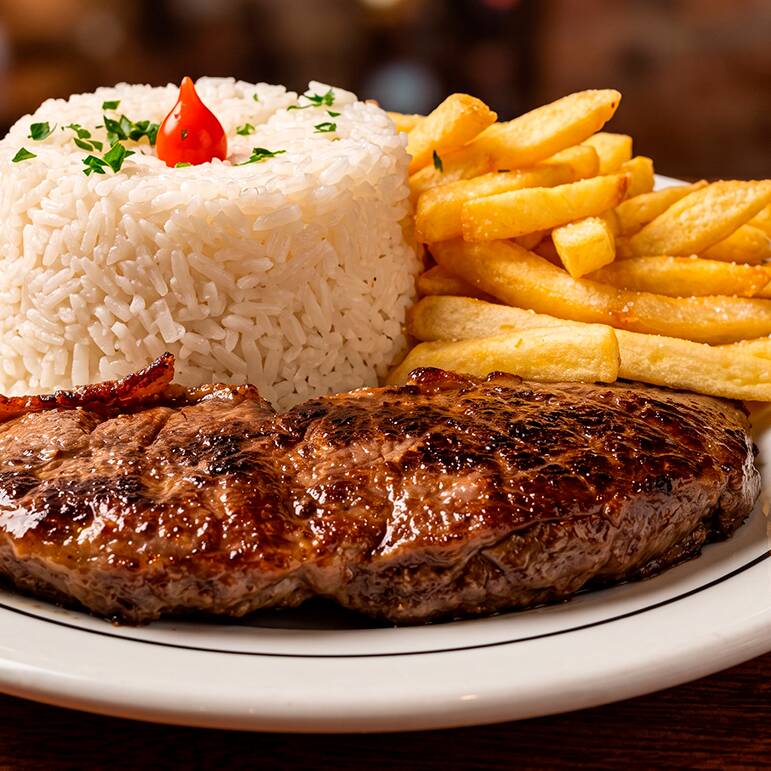 Contrafilé, um corte nobre selecionado por sua maciez e sabor inigualáveis. Grelhado cuidadosamente na brasa para selar toda a sua suculência, este prato executivo é acompanhado por um arroz branco soltinho, Para completar sua experiência, escolha entre a crocância da batata frita ou mandioca frita, ou opte pela leveza da mandioca cozida ou legumes frescos, preparados no ponto perfeito para sua saúde e prazer.