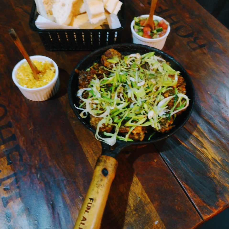 Porção de linguiça de shimeji sabor ervas finas, com alho poró e nirá. Acompanhamento: farofa, vinagrete e pão.