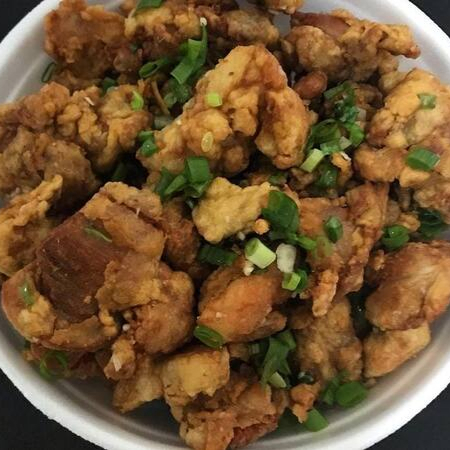 Pedaços de coxa e sobrecoxa desossado frito salpicados com alho e cebolinha