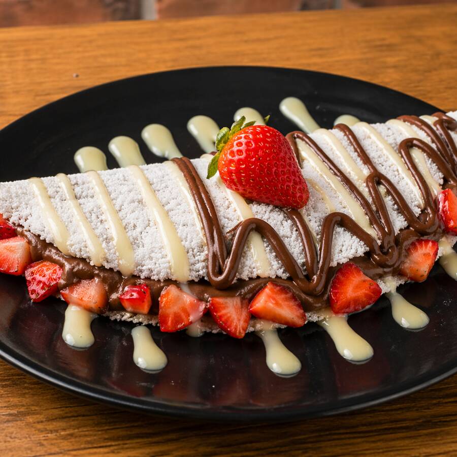 Deliciosa Tapioca Feita Com Massa 100% Artesanal, Recheada Com Chocolate Ao Leite Derretido, Morangos Orgânicos Frescos E Um Toque Generoso De Leite Condensado.