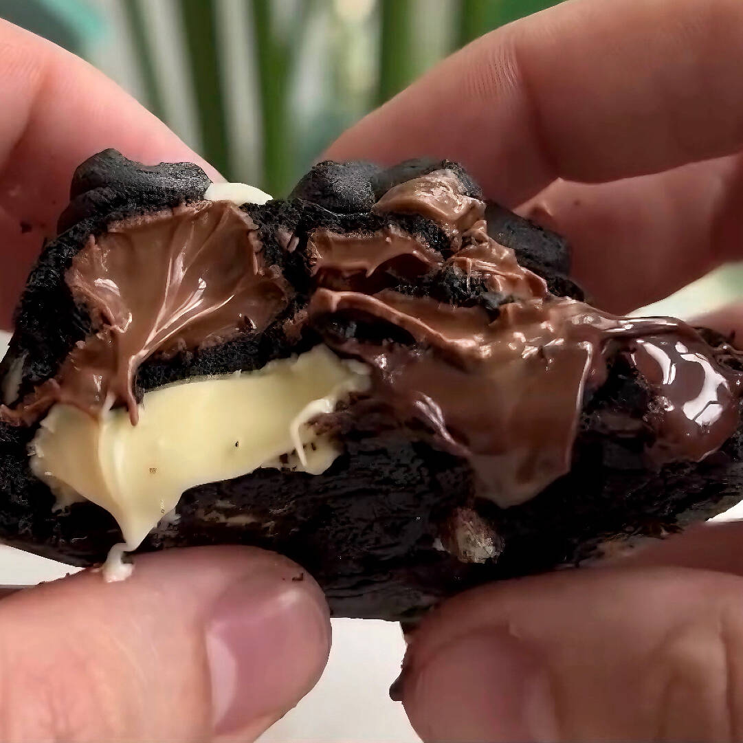 Cookie bem intenso de cacau black com gotas de chocolate branco, chocolate ao leite e com um bombom Alpino no meio.