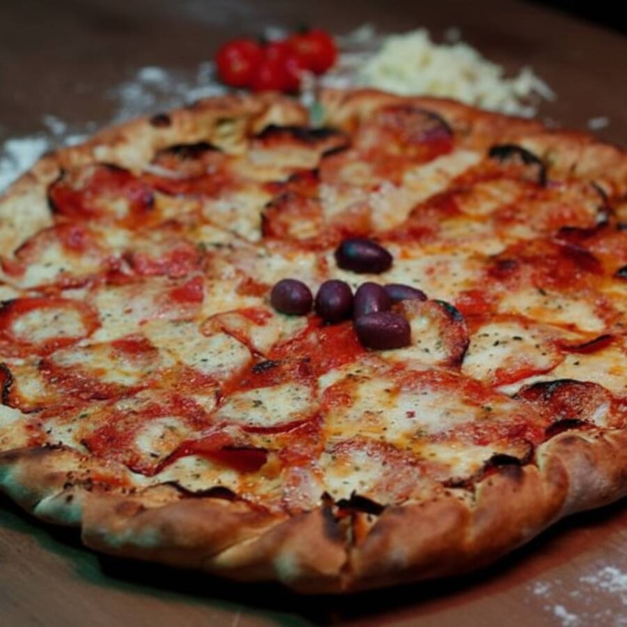 Mozarela e pepperoni fatiado. Pizza acompanha molho de tomate fresco, orégano, azeitonas e gergelim na borda. ***Padrão de massa fina***