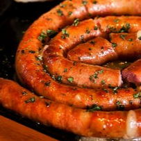 Linguiça caracol de costela bovina angus com farofa crocante e geleia de pimenta.