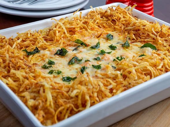 Camarões (18g/cada) refogados com alho e cebola, servido sobre cremoso arroz com manjericão, envolvido com molho branco. Gratinado com queijo mussarela. Acompanha batata palha.