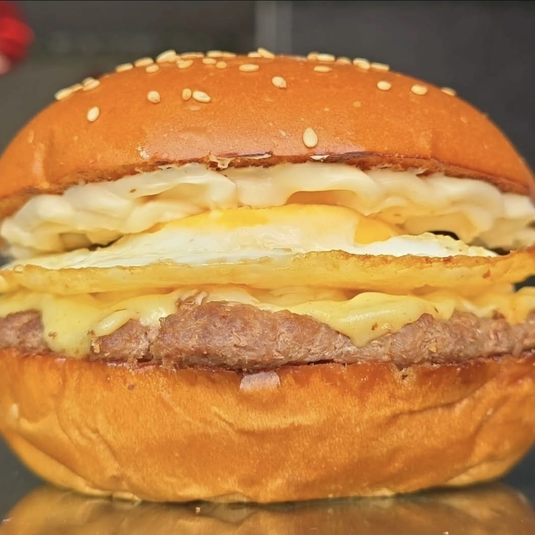 Burger Fininho de 100g (Fake Smash) feito no charbroiler, 2 fatias de queijo prato top, ovo, molho the best suculento em um pão brioche artesanal com gergelim bem fofinho. Obs.: não alteramos o queijo e nem o ponto da carne.