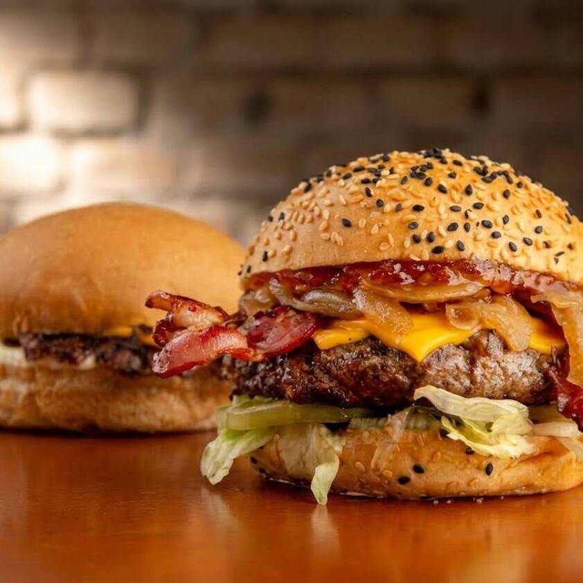 Foi com ele que tudo começou! Burger Angus 180g* ou 120g* grelhado no fogo, cheddar, bacon, geleia de pimenta, cebola caramelizada, no pão selado na manteiga de bacon. Alface e tomate.
