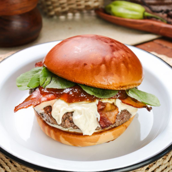 Pão de burguer, blend 150g, cream cheese com tucupi, geléia de taperebá apimentada, fatias de bacon e folhas de agrião.
