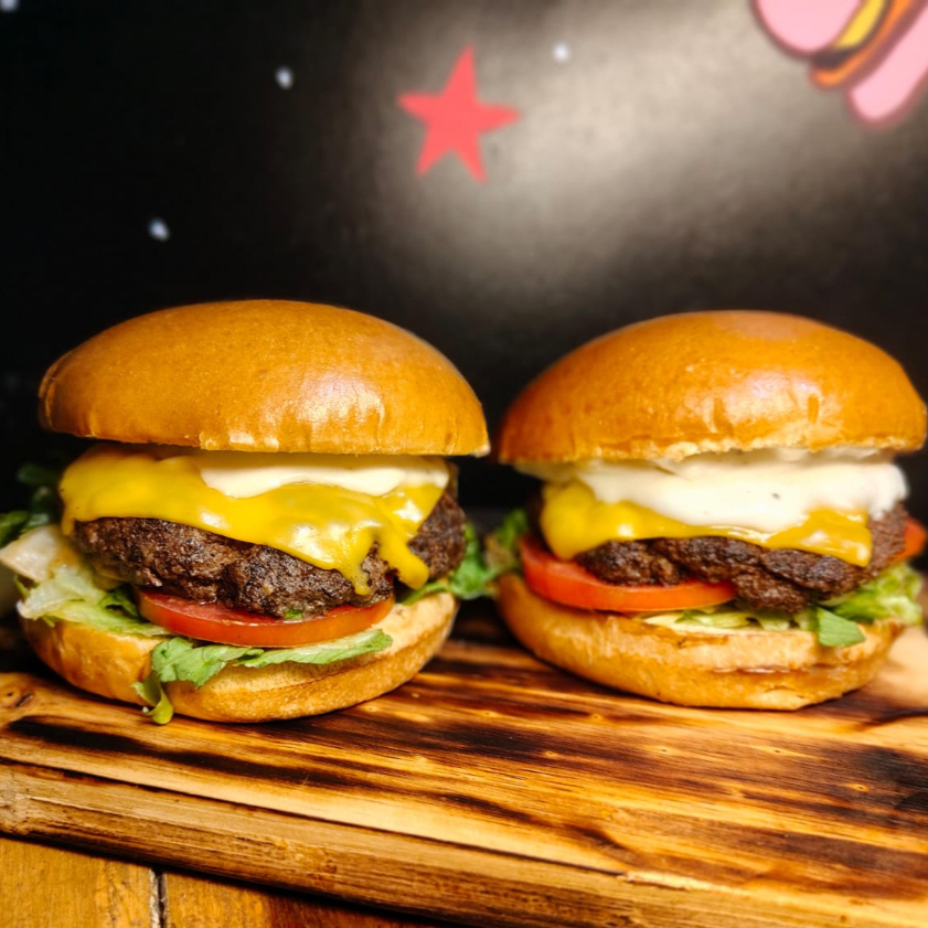 Dois lanches com Pão brioche amanteigado, suculento hambúrguer artesanal Blend 120 gramas cada temperado com especiarias, queijo derretido, cebola caramelizada no molho shoyu, tomate e alface frescos.