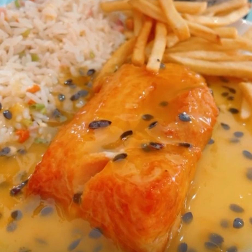 Salmão grelhado ao molho de maracujá, risoto e batata. Um prato que combina a suavidade do salmão com o toque exótico do maracujá.