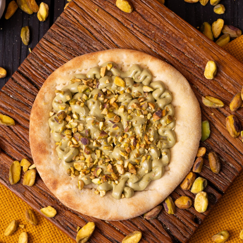 Uma esfiha sofisticada e rica em texturas. Com ingredientes de alta qualidade, essa sobremesa possui um suave creme de pistache coroado com pedaços crocantes dessa castanha triturada. Idealizada para aguçar novos paladares, essa esfiha doce surpreende em todos os sentidos.