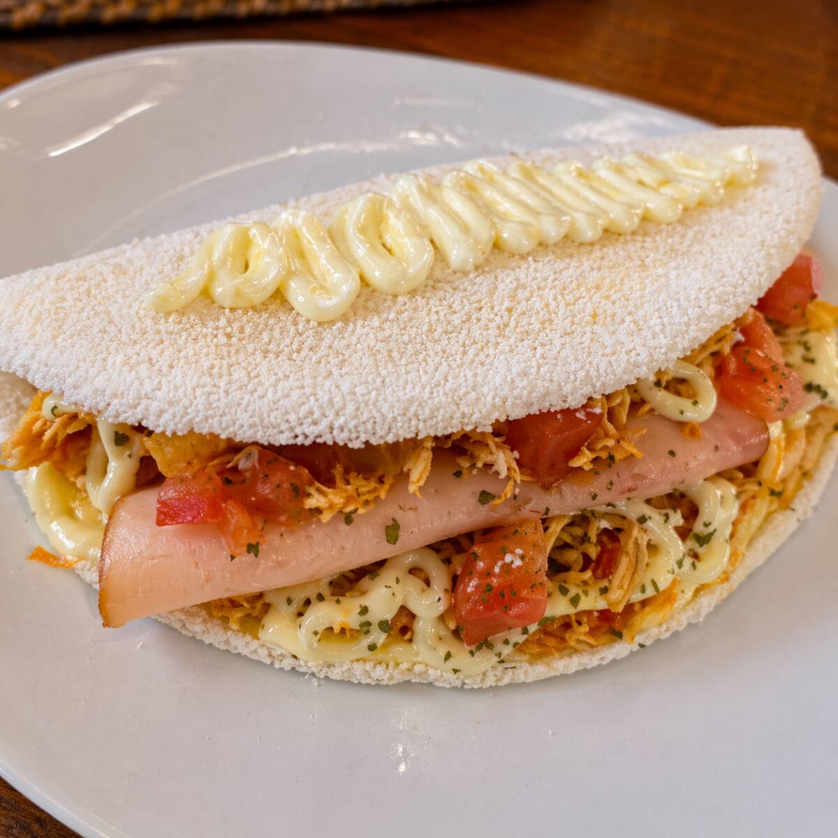 Uma tapioca gourmet preparada na hora, recheada com frango desfiado bem temperado, catupiry cremoso, queijo mussarela derretido, tomate fresco e peito de peru. Uma combinação completa e irresistível, com muito sabor, cremosidade e ingredientes selecionados.