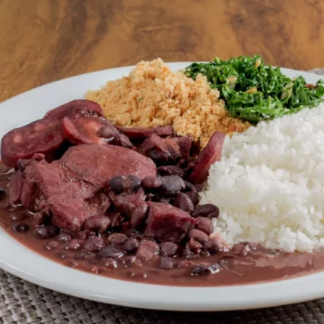 Feijoada Completa com Arroz Branco, Couve Refogada, Farofa, Laranja e Torresmo Crocante. Uma Explosão de Sabor da Nossa Tradição!