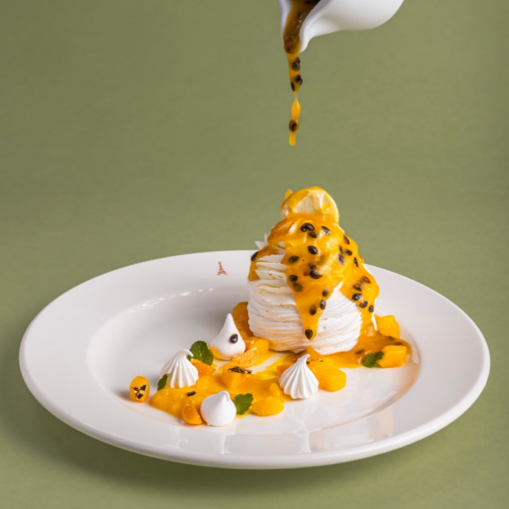 Pavlova leve e crocante por fora, com interior recheado de creme de manga e maracujá, proporcionando um contraste marcante. Finalizada com delicioso coulis de maracujá.