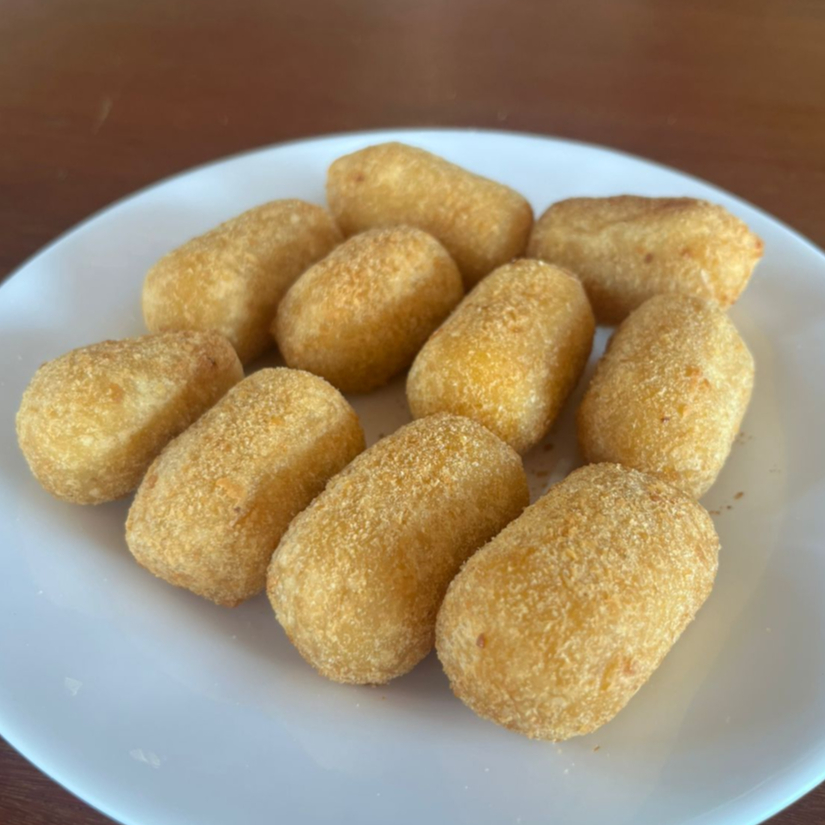 Mini risole dourado com milho suave e queijo Canastra derretido. Perfeito para petiscar.