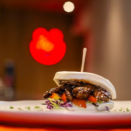 O Classic Bao é um sanduíche asiático servido em um pão bao macio e levemente adocicado, recheado com uma combinação equilibrada de sabores e texturas. Ingredientes: Pão bao macio e vaporoso Lombo suíno Salada crocante, trazendo frescor e leveza Tomatinhos frescos, que adicionam um toque adocicado e ácido Picles de pepino, equilibrando os sabores com acidez e crocância Molho yakisoba, encorpado e levemente adocicado, trazendo um toque umami marcante O resultado é uma explosão de sabores e texturas, unindo o toque macio do bao, a suculência da carne de porco, o frescor dos vegetais e a intensidade do molho yakisoba. Uma opção deliciosa para quem aprecia a culinária asiática com um toque contemporâneo! 2 unidades
