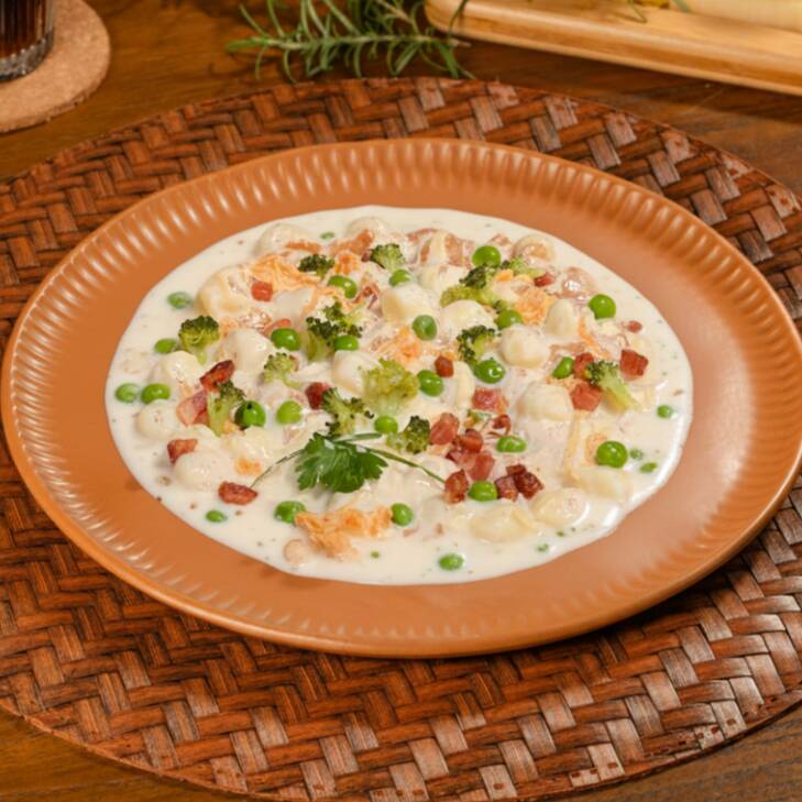 Nhoque de batata cremoso com frango desfiado, ervilha, brócolis e pedacinhos de bacon, tudo envolto em um molho branco suave e delicioso. Uma combinação rica e irresistível!