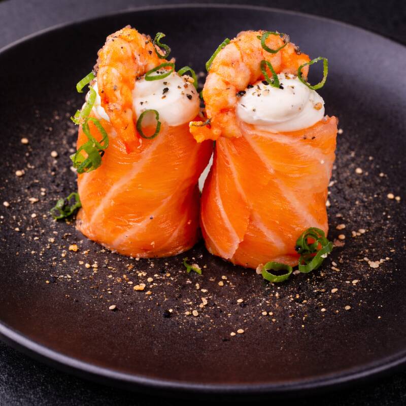Arroz japonês envolvido com lâmina de salmão, envolvido com camarão, cebolinha e gergelim moído.