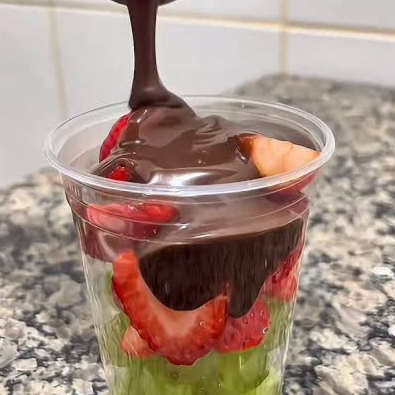 Um delicioso copo com morangos, uvas e chocolate ao leite.