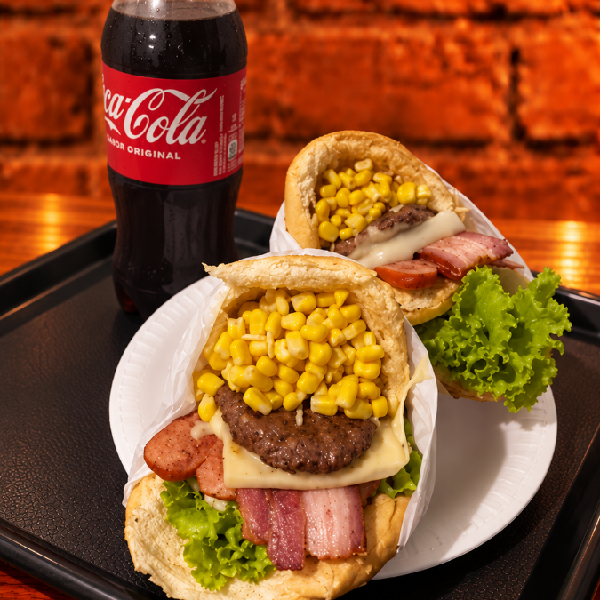 2 X-Tudo (pão, burguer 60g, queijo, presunto, bacon, ovo, salsicha, milho, batata, abacaxi e salada), acompanhados de 1 refrigerante 1L à escolha. Uma combinação caprichada para saborear a dois!