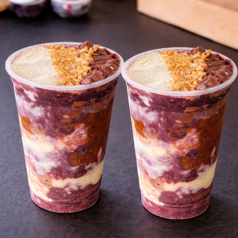 2 Copos 700ml com açaí cremoso e até 5 acompanhamentos grátis. Escolha seus favoritos e aproveite!