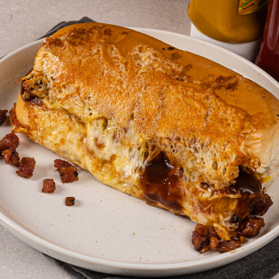 Pao macio, salsicha temperada, ketchup, mostarda, maionese, purê de batatas, batata palha, milho, vinagrete, Catupiry, cheddar e molho barbecue, casquinha de queijo, bacon e maionese caseira. Lanche prensado!