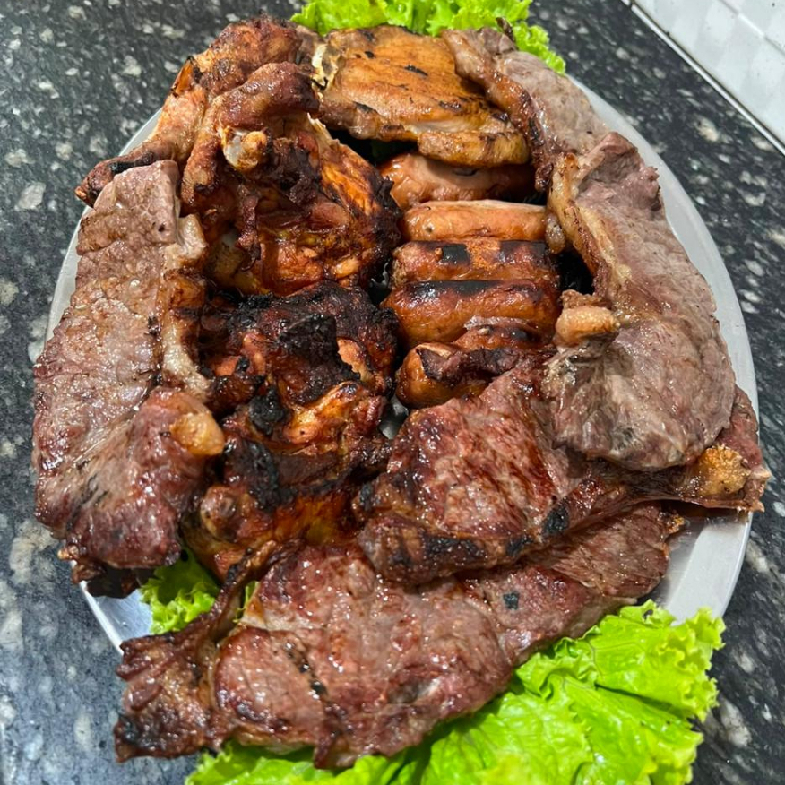 5 fatias de filé especial, 5 coxas de frango, 5 toscanas e 1 fatia de bisteca suína. Acompanhamentos: feijão tropeiro, arroz branco, macarrão, salada mista (2 opções) e purê de batata. Serve até 5 pessoas.