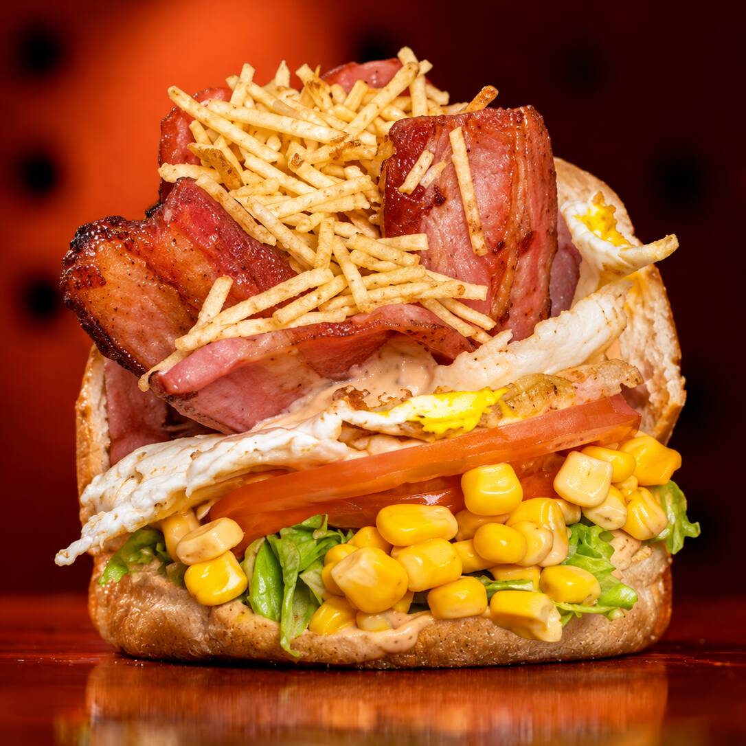 Pão com hambúrguer(100g), queijo, presunto, bacon crocante, ovos, tomate, alface, milho e batata palha. Um lanche reforçado, bem recheado e cheio de sabor.