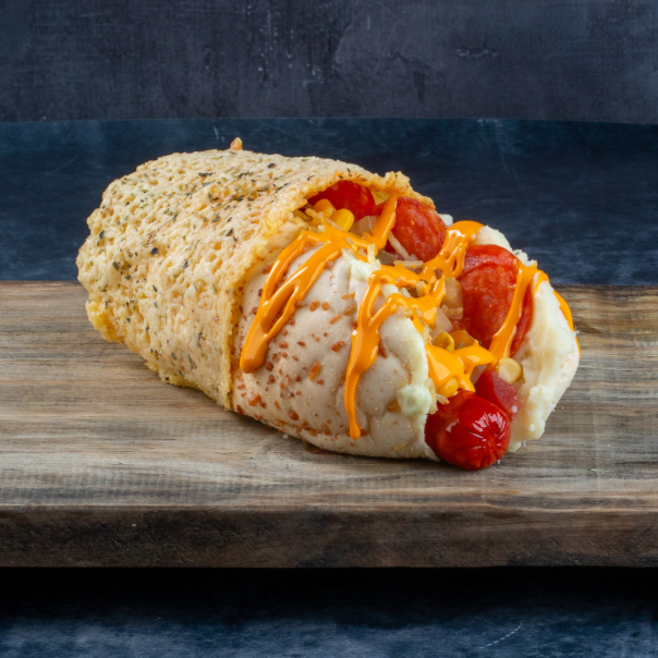 1 salsicha hot dog (ou troque sua salsicha), cheddar ou requeijão, milho, vinagrete, batata palha, maionese, purê, orégano, curry, pepperoni, marinara mexicana (picante) e coberto por uma deliciosa crosta de parmesão.