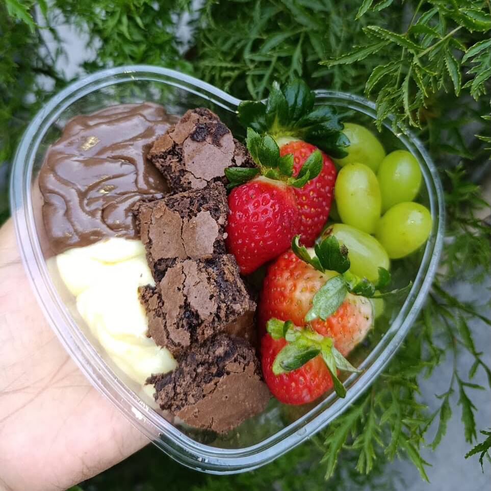 Feito para celebrar o amor! Camadas generosas de brownie artesanal, creme aveludado, chocolate cremoso, morangos frescos e uvas doces em uma explosão de sabores que conquista na primeira colherada.