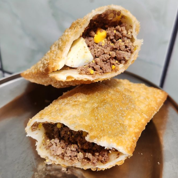 Pastel completo com carne moída, tomate, ovo cozido e azeitonas, uma refeição completa em um só pastel.