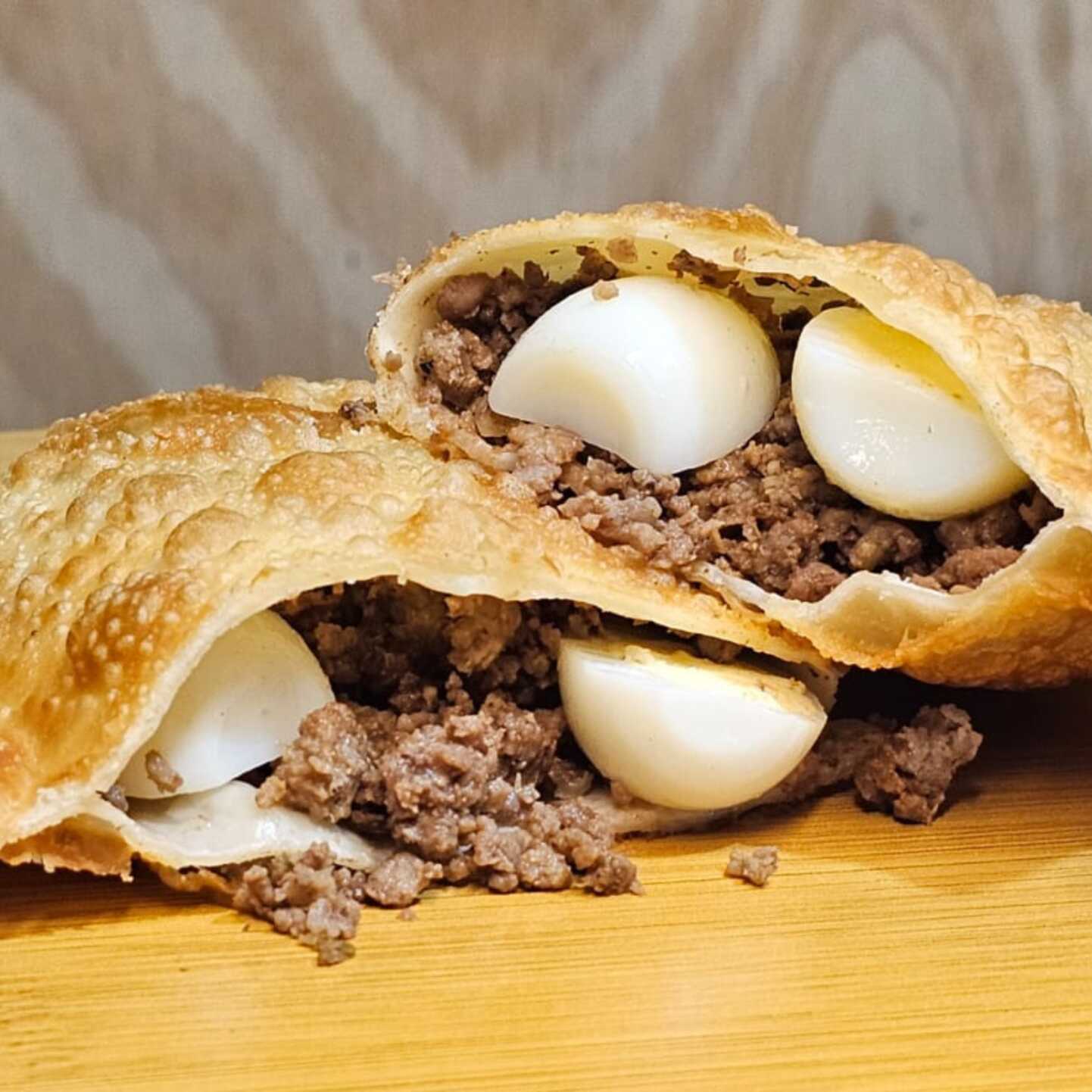 Delicioso pastel crocante recheado com suculenta carne moída e ovo cozido, uma explosão de sabores tradicionais irresistíveis.