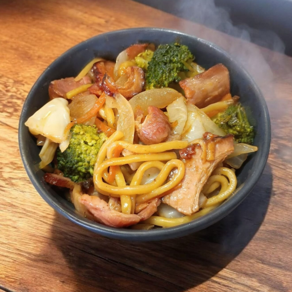 Macarrão oriental premium frito, repolho, cebola, cenoura, brócolis e fatias de Bacon Defumado. Tudo salteado e envolvido por um molho à base de shoyu. Suculento e sabor intenso. Nosso molho pode conter gengibre, óleo de gergelim, peixe e soja. O macarrão pode conter trigo, ovos e leite.