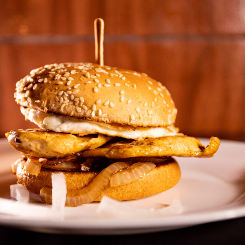 Pão gergelim , peito de frango , 2 queijos , cebola ao molho shoyo , ovo , maionese temperada , cheddar cremoso , ketchup e alface .