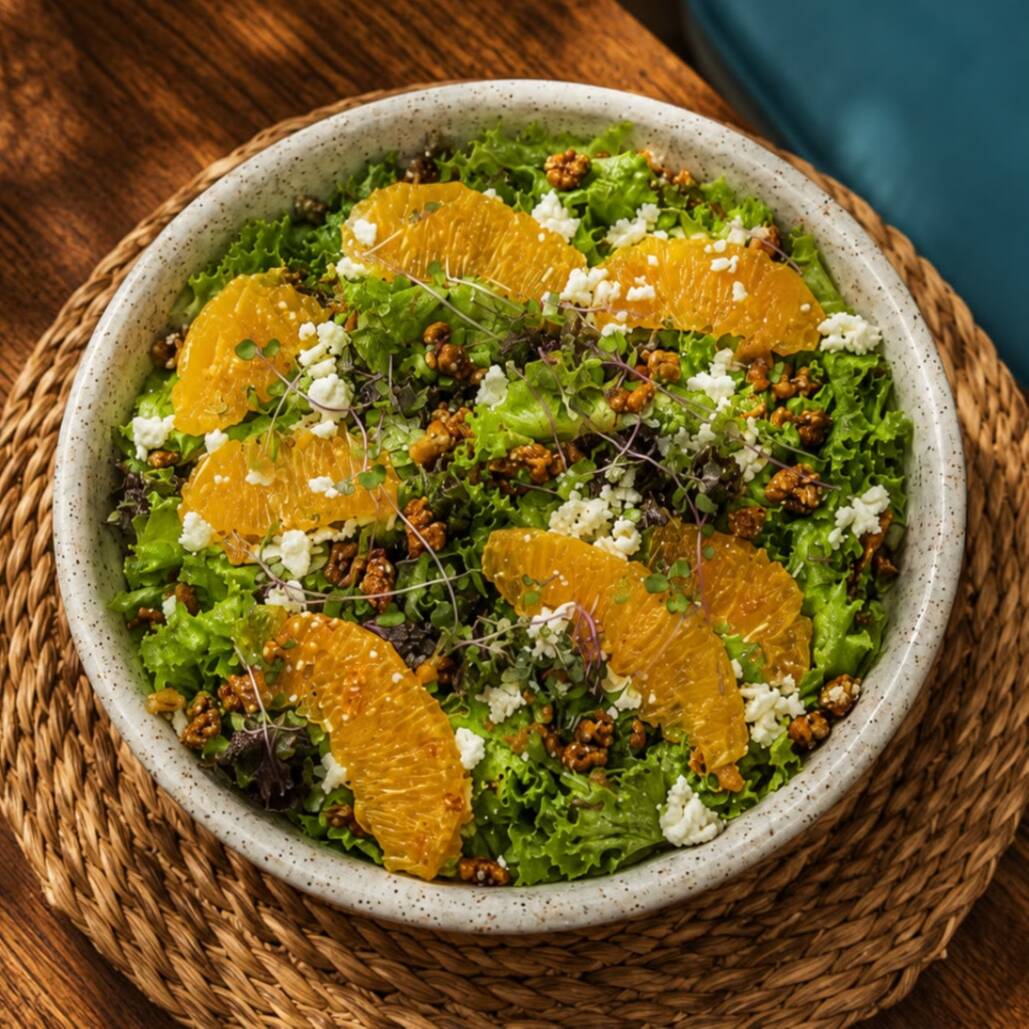 Mix de folhas, gomos de laranja, queijo de cabra, nuts caramelizadas e molho de mostarda.