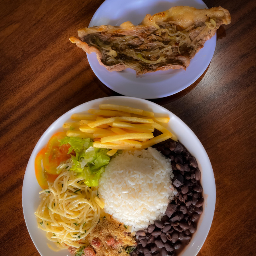 Aroz branco, feijão, farofa, macarrão, refogado do dia, batata frita, salada de alface americana e tomate e Bife acebolado
