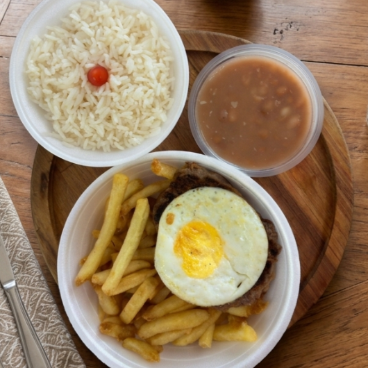 Suculento bife com ovo estrelado, acompanhado de arroz soltinho, feijão caseiro, batata frita crocante.